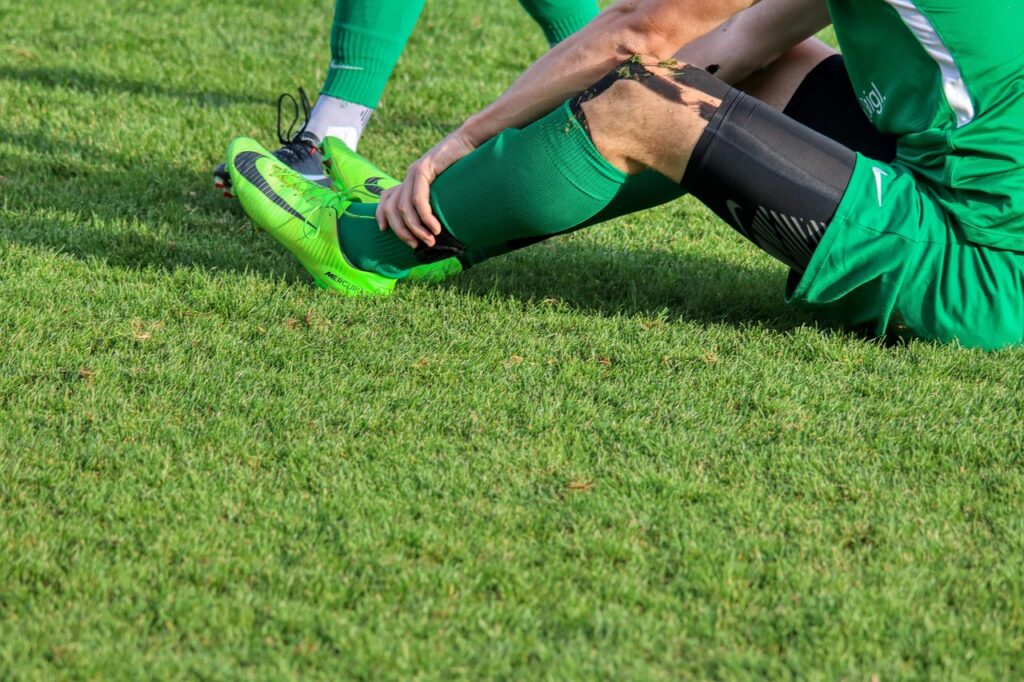 A sports player holding their leg after a fall, highlighting the risks that may lead to a slip and fall injury compensation claim.