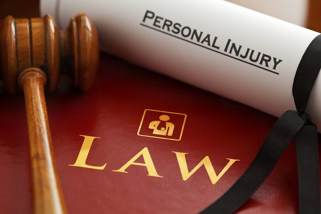 Gavel resting on a red law book with a rolled-up document labeled “Personal Injury,” symbolising legal action after an injury.