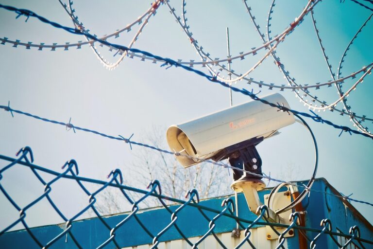 Security camera and barbed wire surrounding a border fence, symbolising enforcement of the Illegal Entry UK border rules.