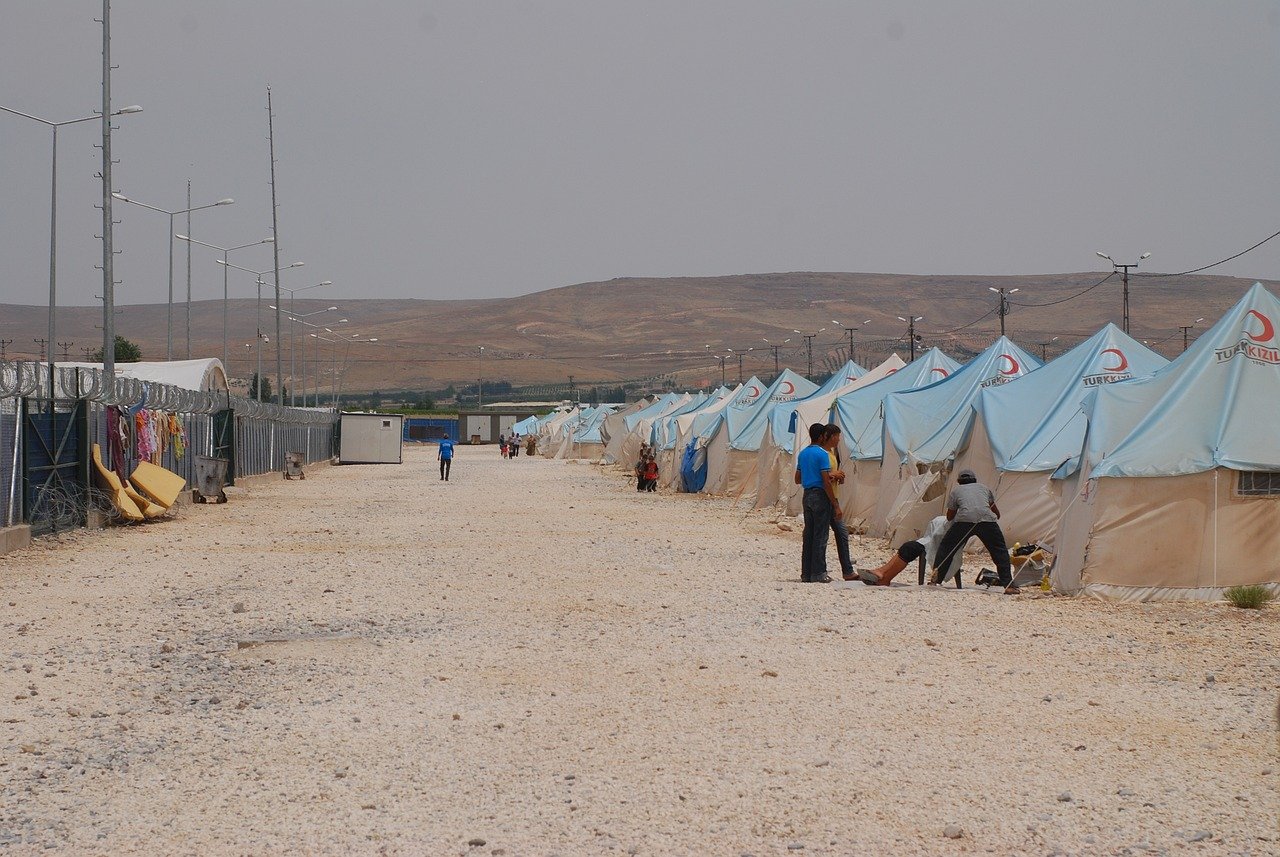Refugee camp with tents and aid workers in a remote area, representing lives impacted by Illegal Entry UK policy changes.