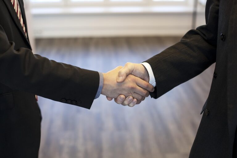Two professionals shaking hands in a formal setting, symbolising trust and agreement in setting up Personal Injury Trusts.