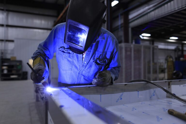 A skilled worker welding metal inside a manufacturing facility in the UK – affected by Skilled Worker Changes 2025.