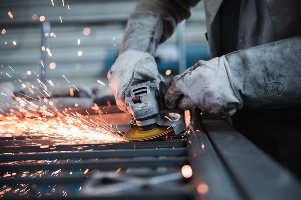 Close-up of a skilled worker grinding metal with protective gloves – illustrating key Skilled Worker Changes in the UK job market.