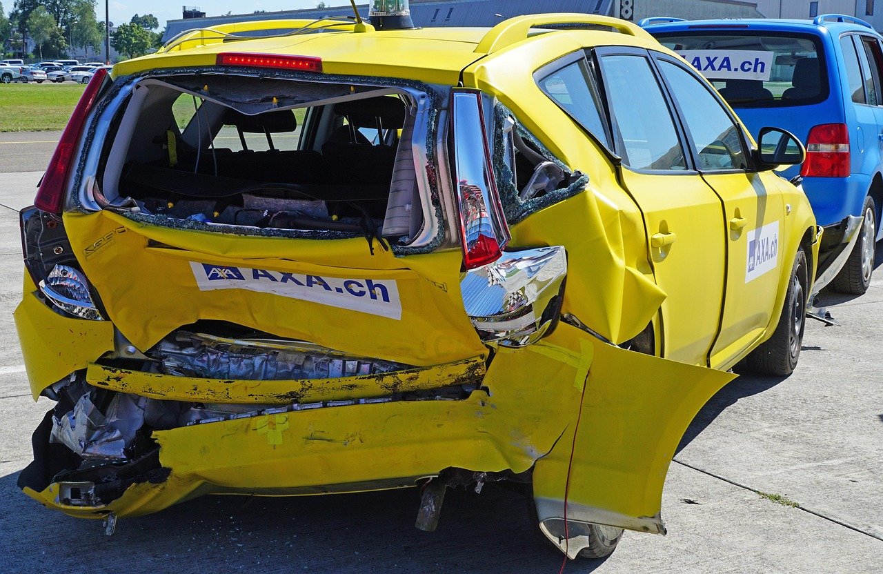 Car accident insurance claim photo of a yellow car with severe rear damage after a crash.