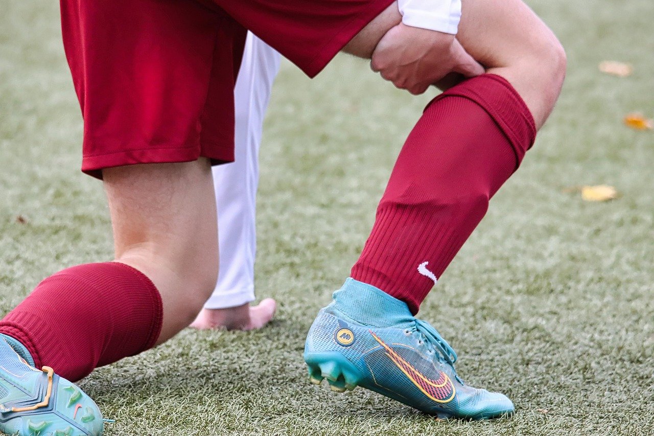 Football player holding leg after injury on the pitch, highlighting situations that may lead to Sports Injury Claims.