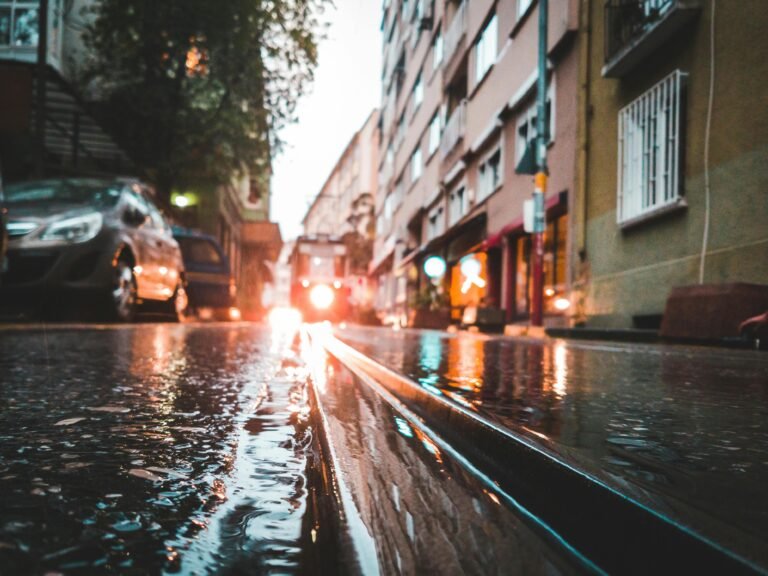Wet city street with standing water after heavy rain, illustrating potential Escape of Water Injury risks.