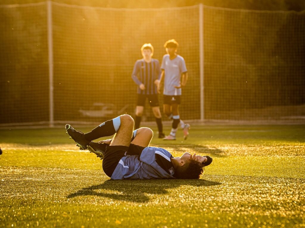 Football player lying on the ground in pain after a tackle, a common example relevant to Sports Injury Claims in the UK.