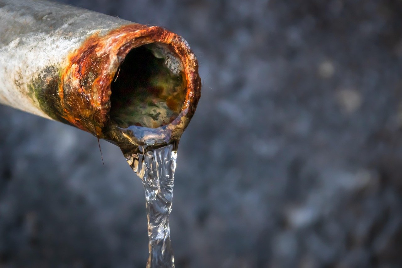 Rusty leaking pipe releasing water, a common source of Escape of Water Injury accidents and property damage.