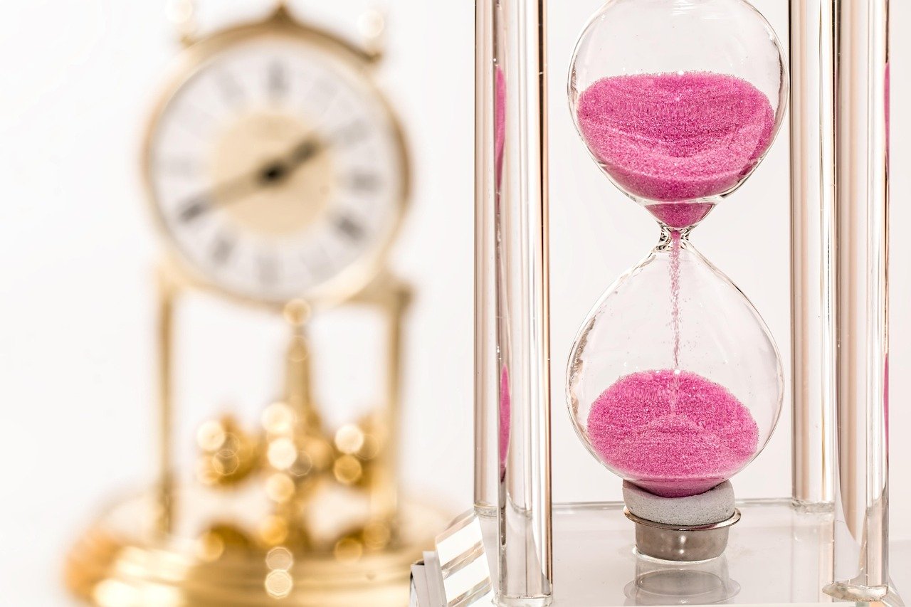 An hourglass with pink sand and a blurred clock in the background, symbolising the limitation period UK for personal injury claims.